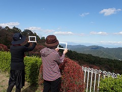 フレームを使って景色を切り取り楽しむハイキング参加者の後ろ姿