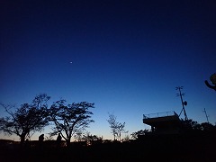 青のグラデーションが綺麗な夕暮れの空、広場から見上げている