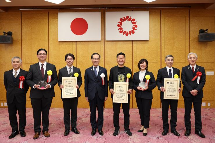 表彰式で訪問者と集合写真を撮る知事の写真